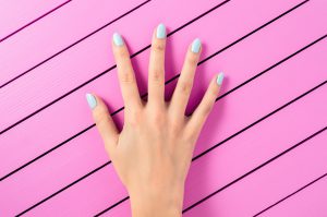 Beautiful female hand with blue nails over pink background